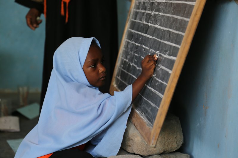 (A little girl writes numbers from 1 to 5 on the blackboard at Mnyimbi TuTu Center in Zanzibar. Tanzania, April 2017 Photo Credit: GPE/Chantal Rigaud)